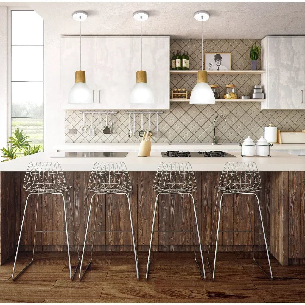 Três pendentes modernos iluminando bancada de cozinha com banquetas de metal.