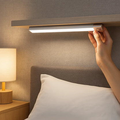 Luminária de LED slim instalada sob prateleira de madeira em quarto aconchegante.