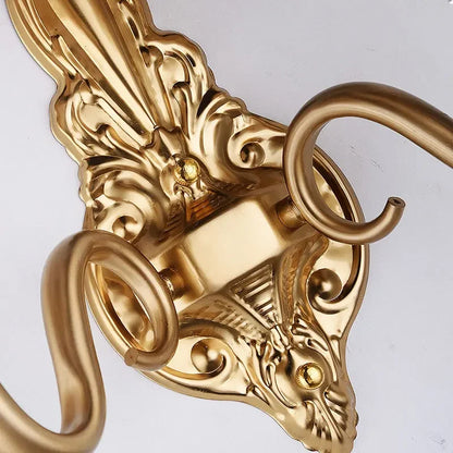 Detalhe de luminária de parede clássica com acabamento dourado e ornamentos rebuscados.