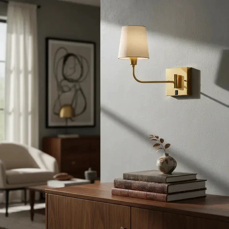 Arandela de parede dourada com cúpula de tecido em ambiente de sala decorada.