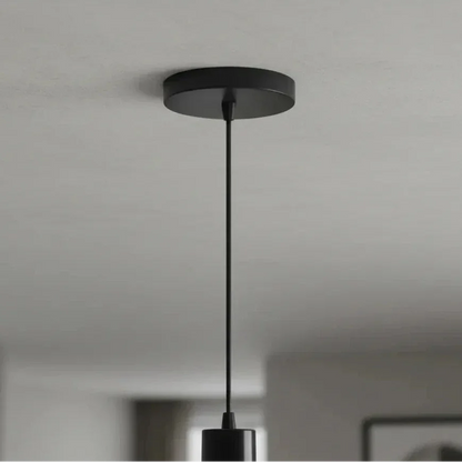 Pendente preto minimalista com cabo fino suspenso no teto branco.