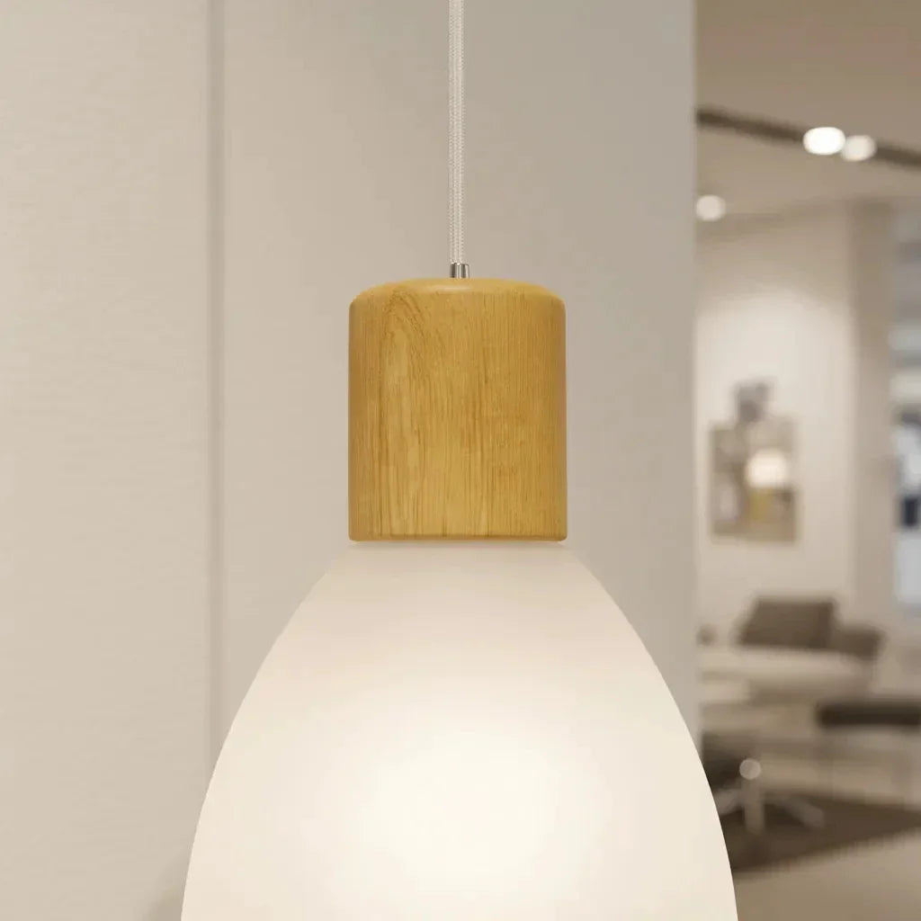 Luminária pendente moderna com cúpula de vidro branco fosco e detalhe em madeira clara.