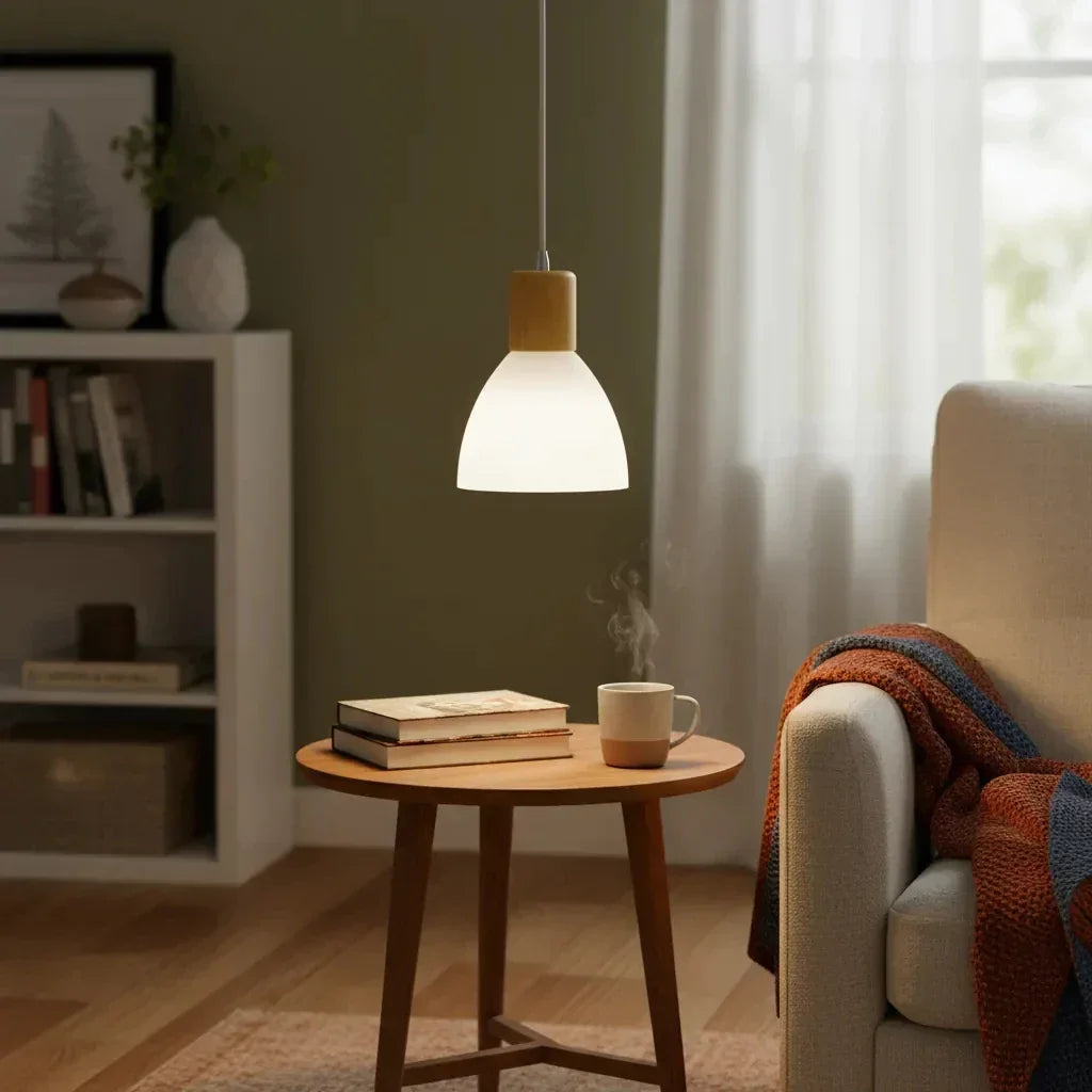 Luminária pendente moderna iluminando mesa lateral com livros e xícara de café em sala aconchegante.