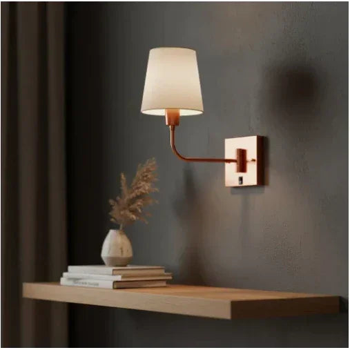 Arandela de parede moderna com cúpula branca e acabamento em cobre sobre prateleira decorativa.